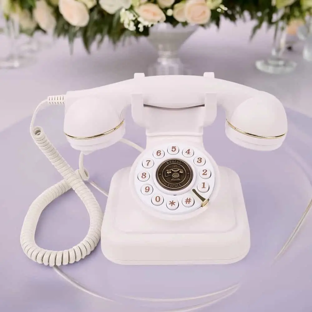 Telefon retro alb Elegance70 White pe o masă lila, sub aranjamente florale
