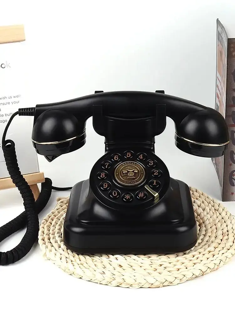 Telefon retro negru cu disc auriu, pe un suport rotund împletit